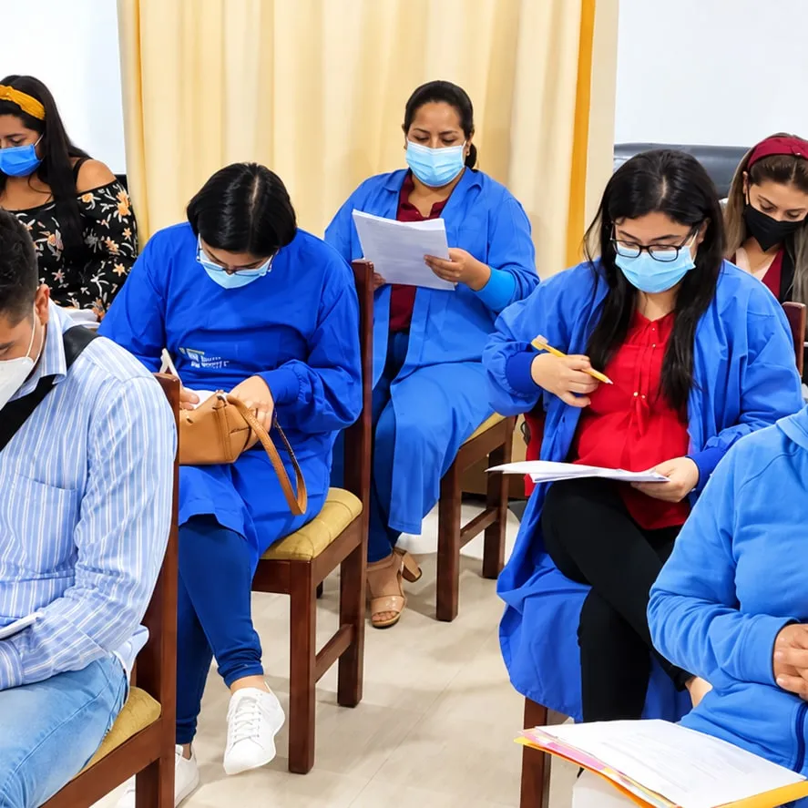 Integrantes del equipo del hospital, con mascarilla, revisando documentos sentados en una sala.