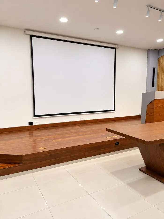 La tarima del auditorio, con la pantalla de proyección y el atril.