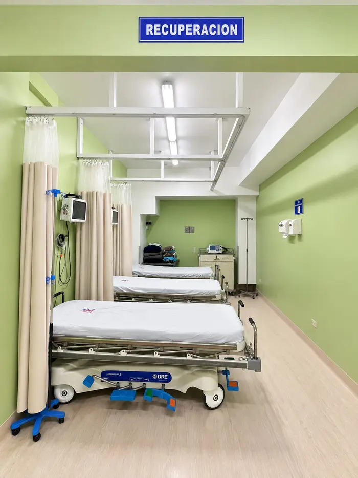 La entrada a la sala de recuperación, con su rótulo y las camillas separadas por cortinas.